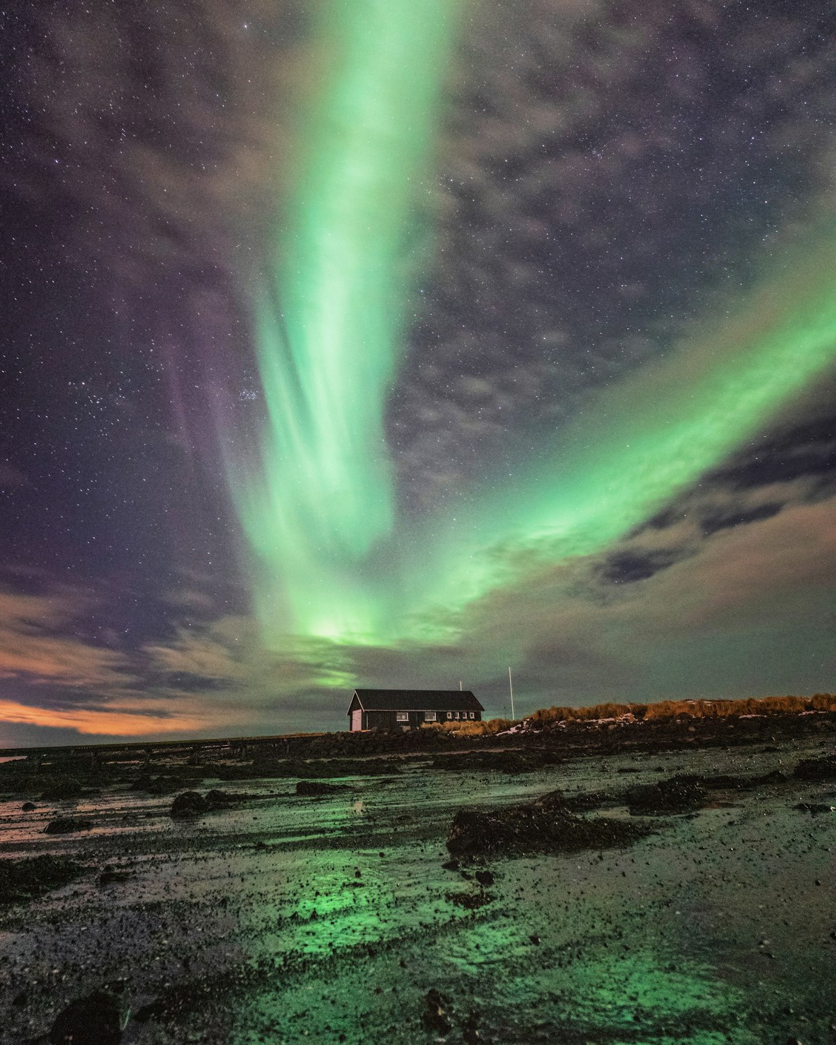 Green aurora arcing over the sea and the small lighthouse island at Grótta on the western tip of Seltjarnarnes, Reykjavík.