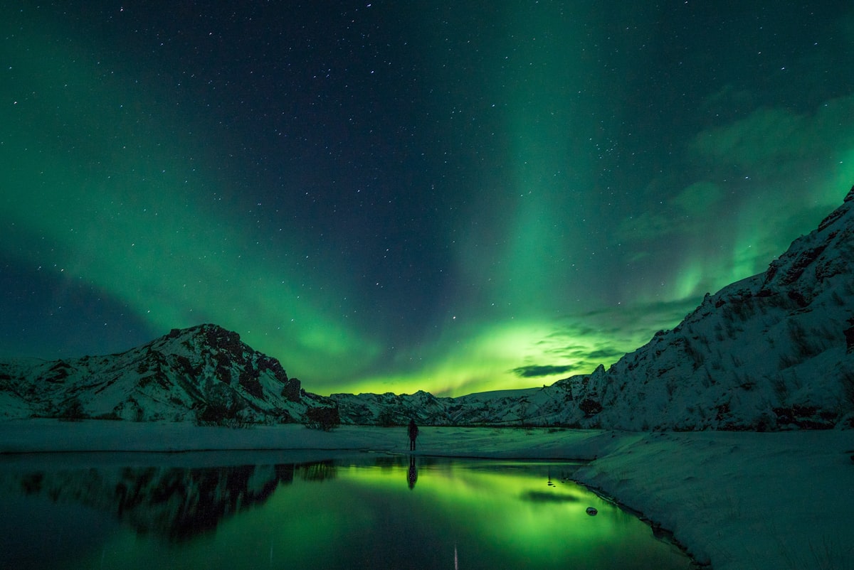 Green northern lights arcing over a dark Icelandic landscape — the kind of display a strong solar storm produces once the sky is dark enough to see it